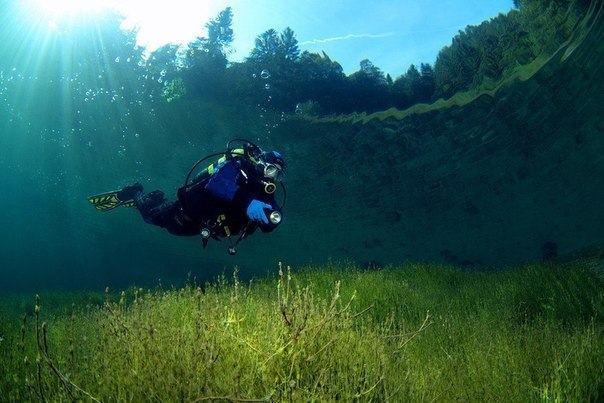 Водолаз плавает в кристально чистом озере Sameranger в Тироле, Австрия. Фотография была сделана на глубине 