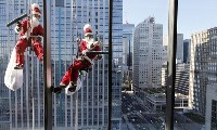 Мойщики окон в костюмах Санта Клаусов работают на фасаде гостиницы в деловом районе Токио
